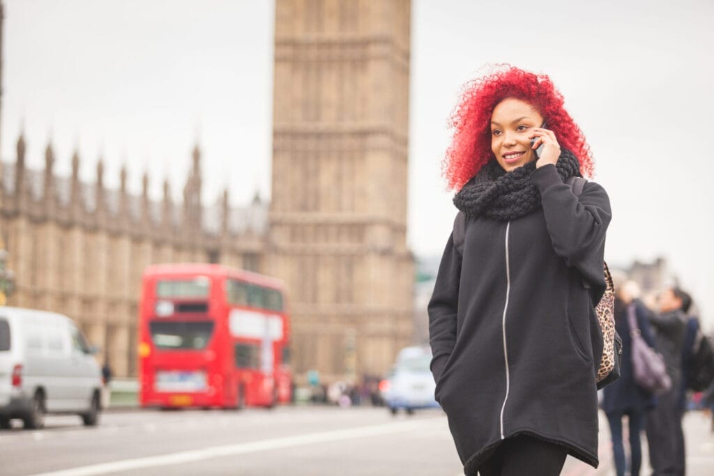 Beautiful woman talking on mobile in London with Big Ben and Westminster palace in background.